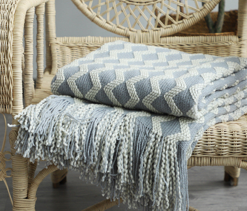 Blue and white patterned throw blanket draped over a wicker chair.