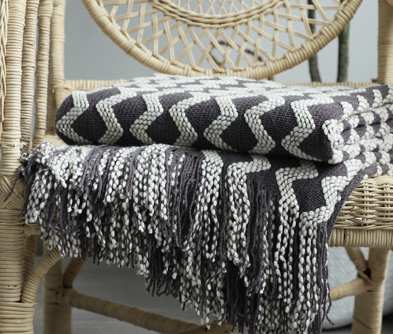 image Textured black and white blanket draped over a wicker chair