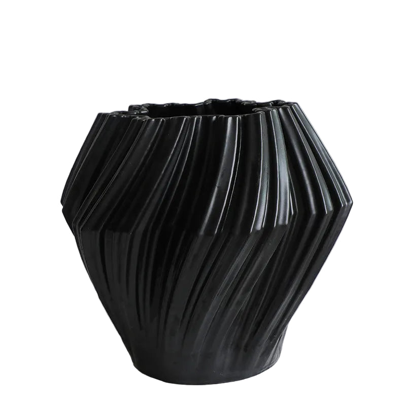 Black textured vase on a white surface with a light gray background