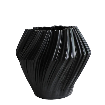Black textured vase on a white surface with a light gray background
