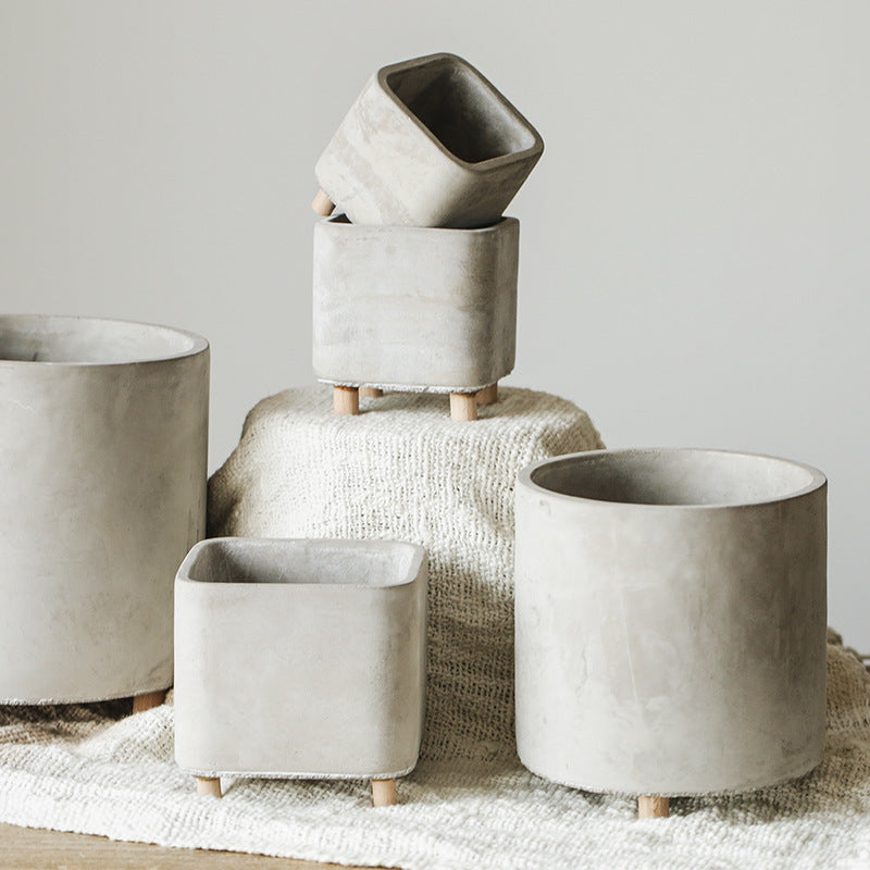Set of concrete planters in various shapes and sizes on a textured surface.