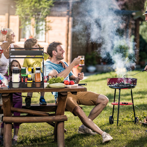 People enjoying a barbecue in a garden with a man holding a beer.