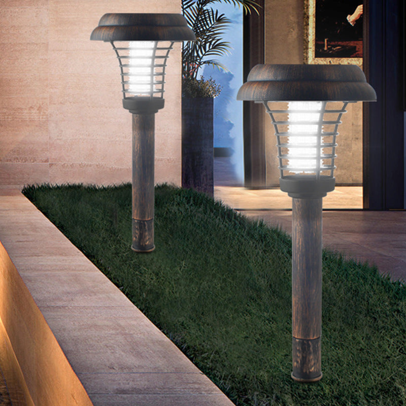 Two solar-powered outdoor lamps on grass with a building interior in the background