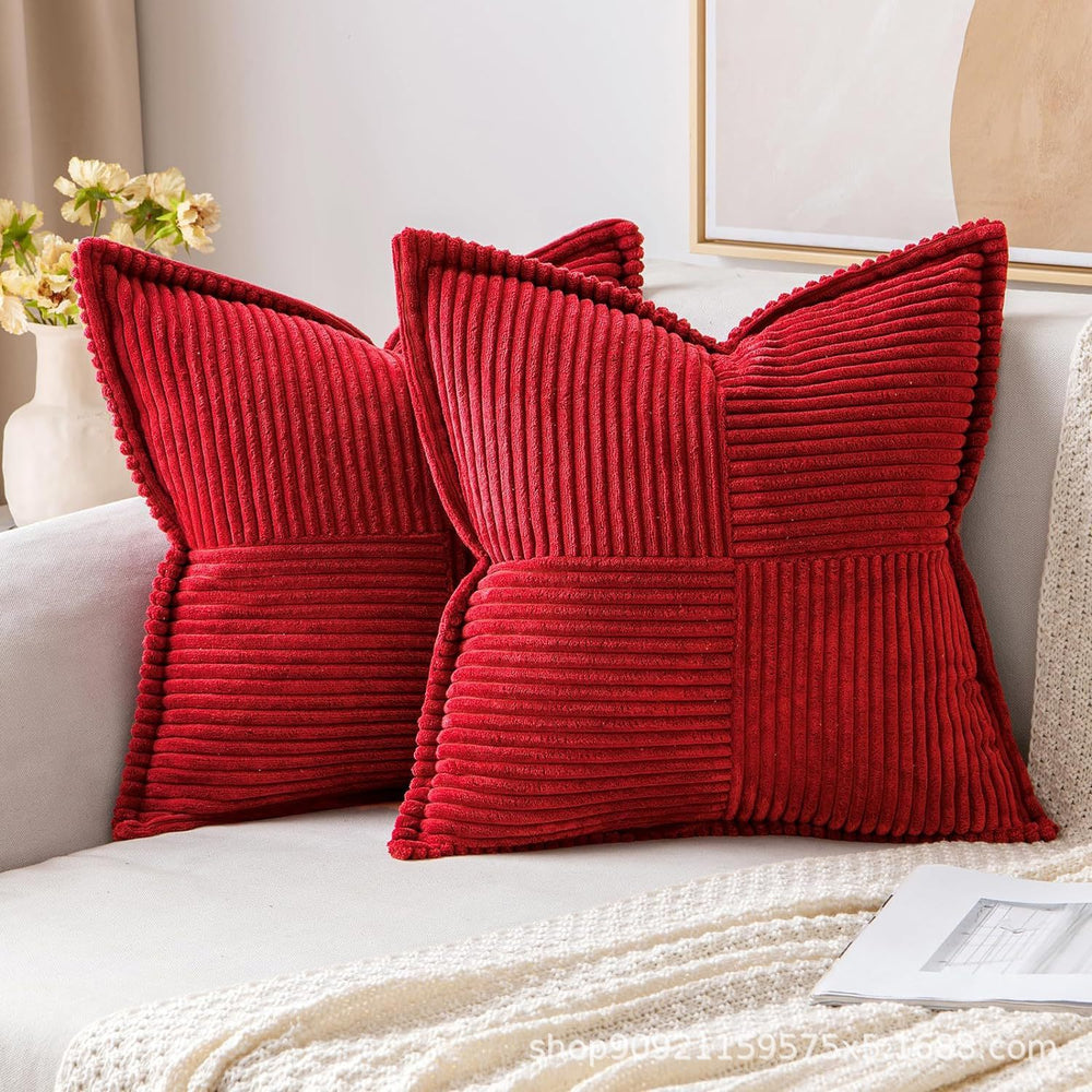 Two red textured pillows on a white sofa with a neutral background