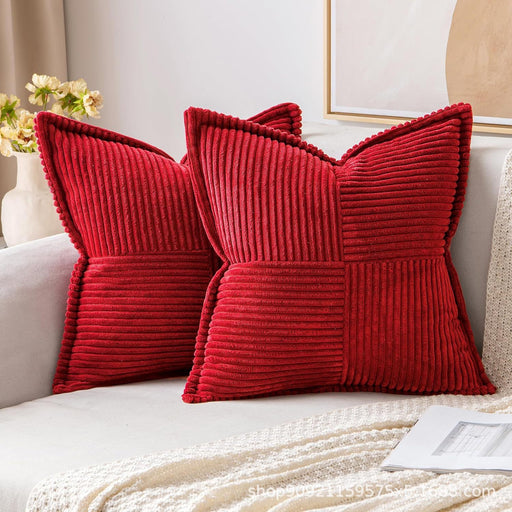 Two red textured pillows on a white sofa with a neutral background