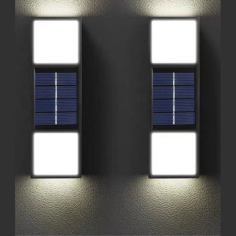 Two solar-powered wall lights on a dark wall.