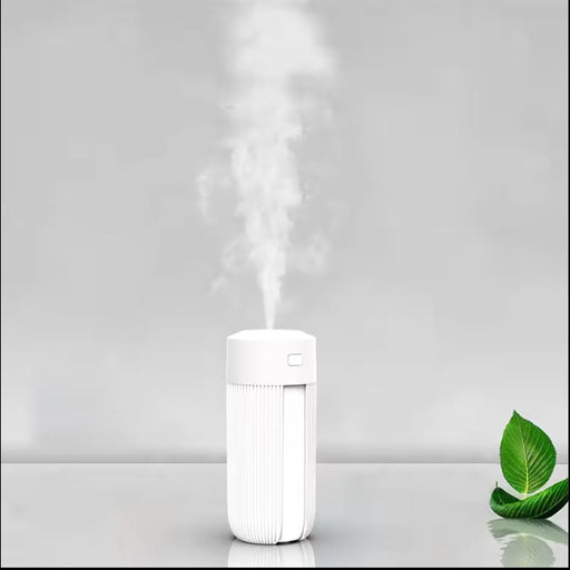 White humidifier emitting steam on a gray background with a green leaf