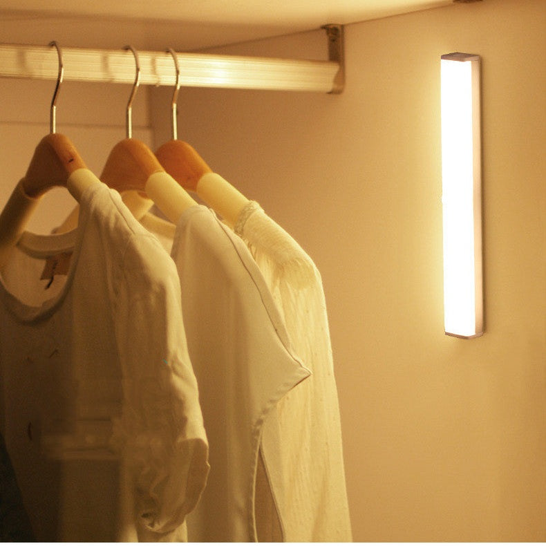 Clothing on hangers with a wall-mounted light in a closet