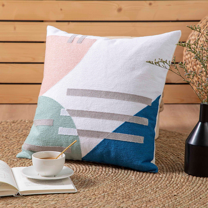 image Decorative pillow with geometric pattern on a wooden surface with a cup and book.