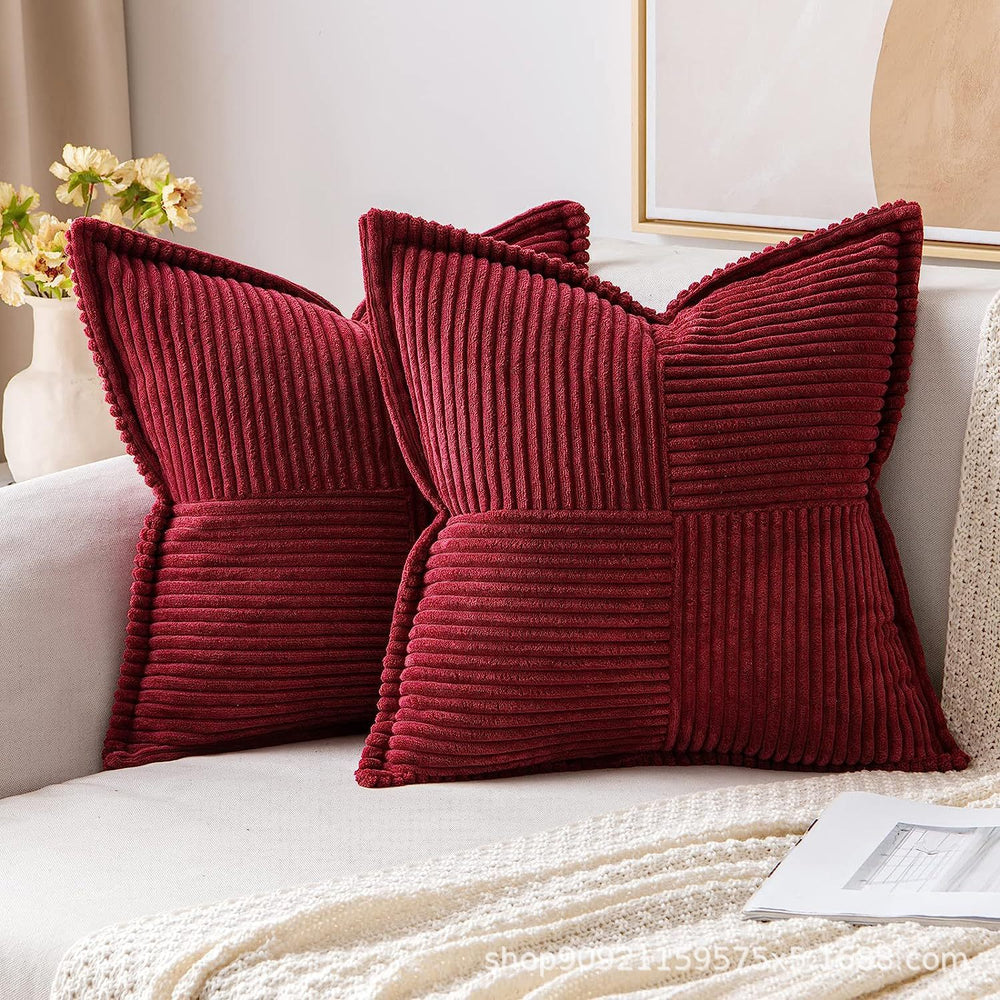 Two red textured pillows on a white sofa with a neutral background