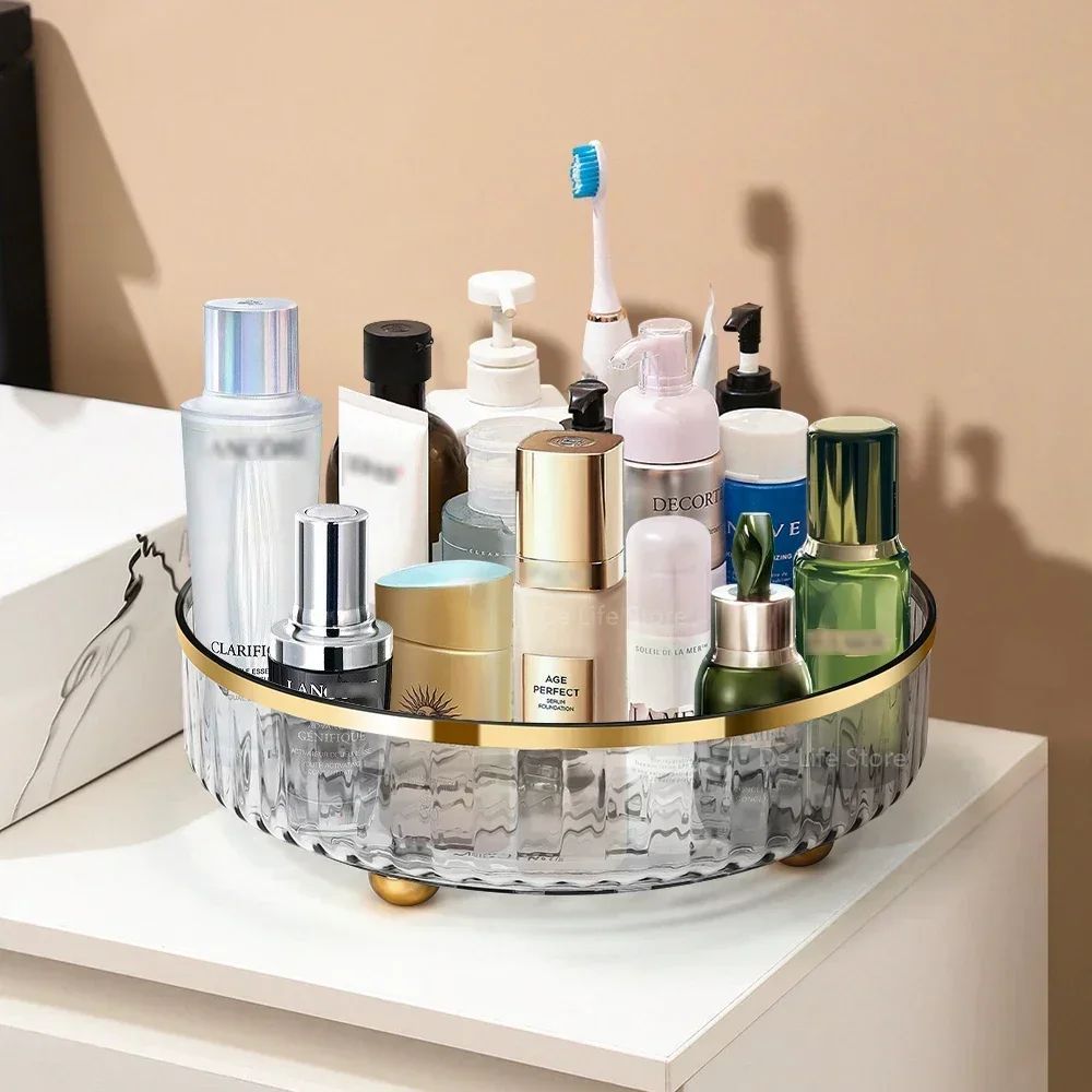 Bathroom counter with a round glass tray holding various skincare products and a toothbrush.