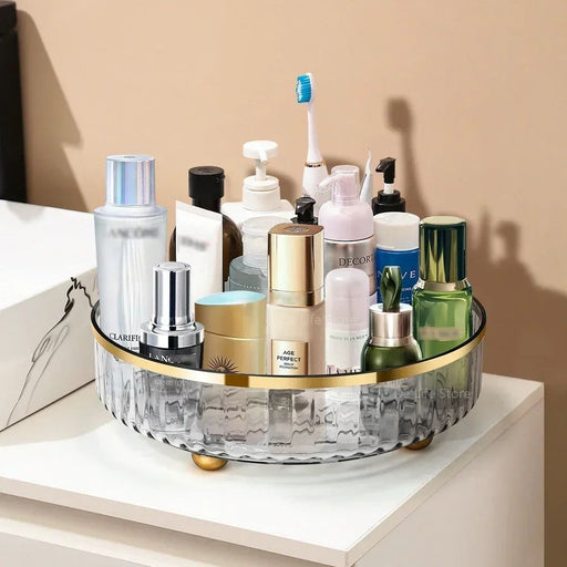 Bathroom counter with a round glass tray holding various skincare products and a toothbrush.