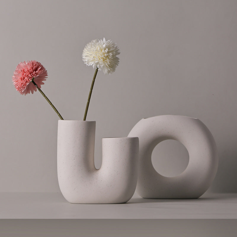 Two modern concrete vases with flowers against a plain background