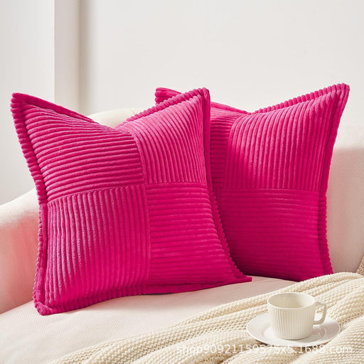 Two pink textured pillows on a couch with a cup and saucer in the foreground.