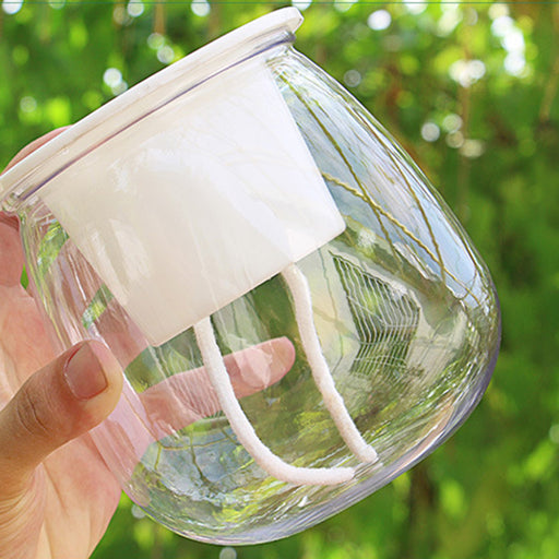 Clear glass jar with white lid held by a hand against a green blurred background