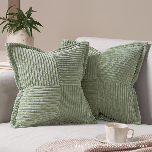 Green textured pillows on a sofa with a plant and cup in the background
