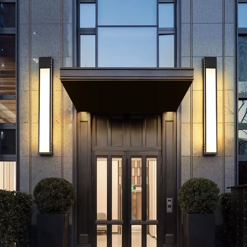 Modern building entrance with glass doors and illuminated wall lights.
